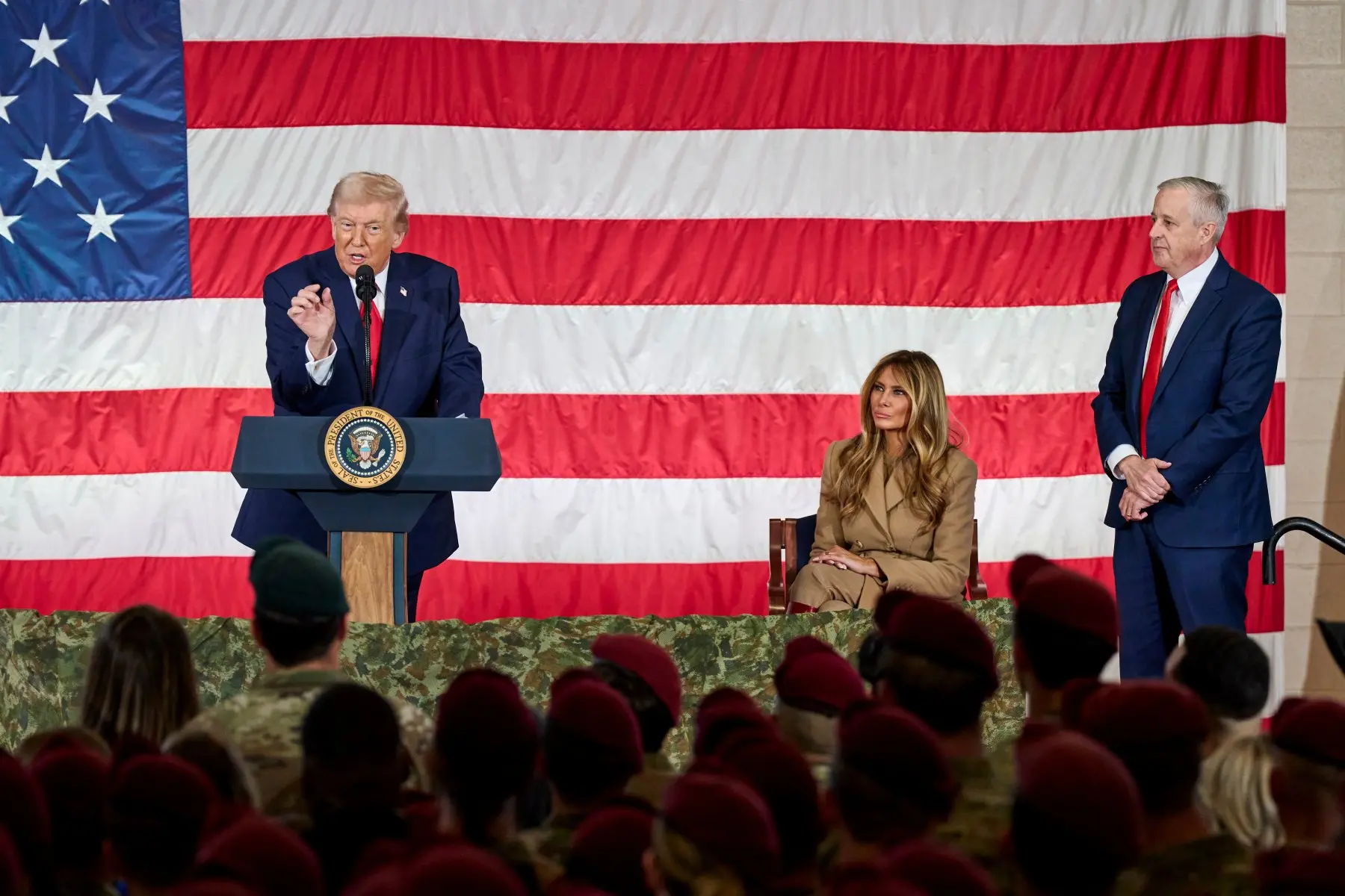 Donald Trump speaking at a podium bearing the presidential seal in front of an American flag