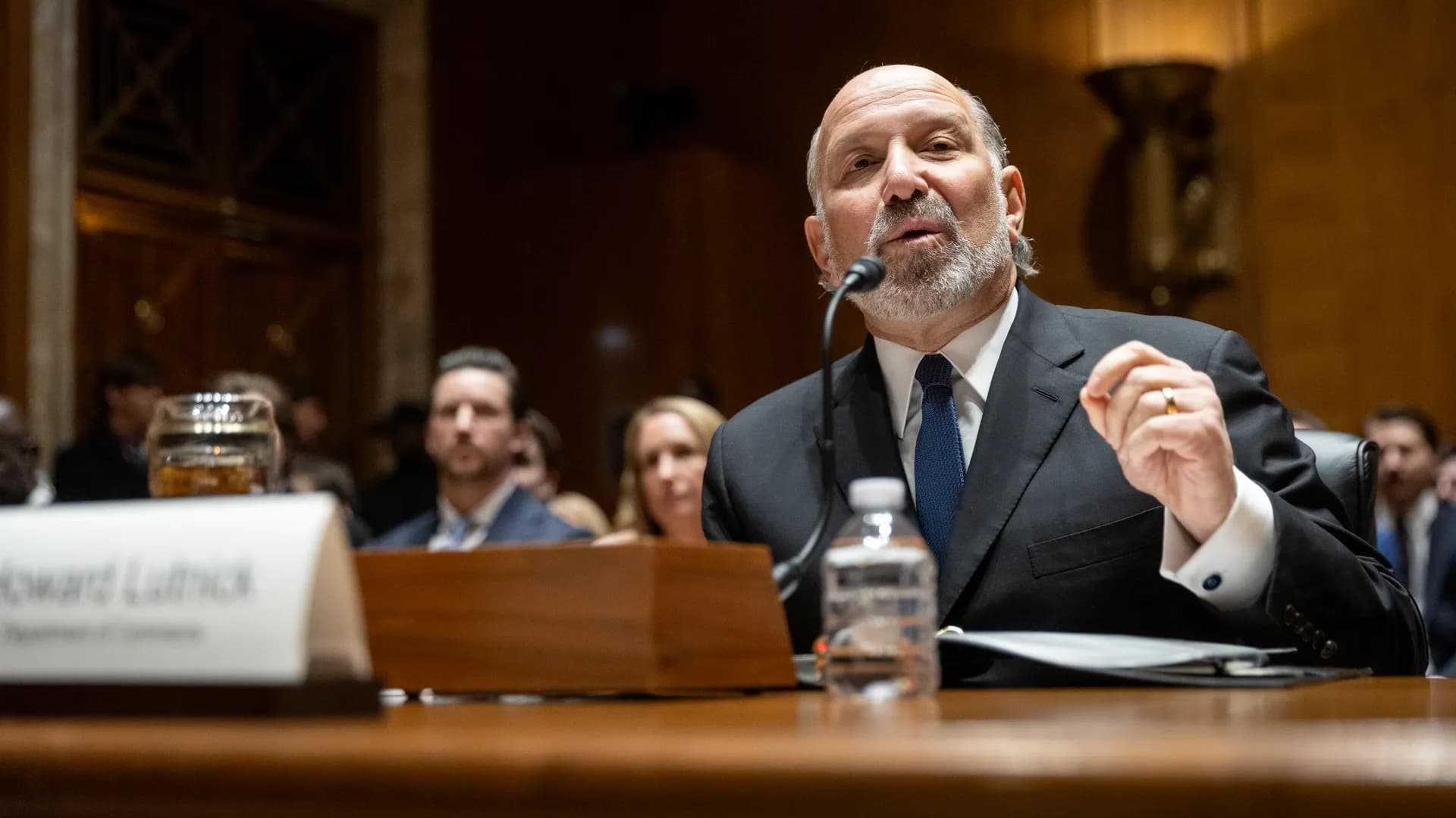 Howard Lutnick testifying before a congressional committee, seated at a microphone with his name placard